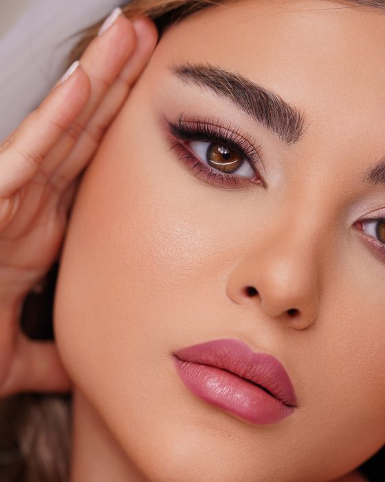 Kühle Pflaumen- und Mauve-Nuancen rahmen die Augen weich ein, während natürliche Nude-Lippen den Look klar, elegant und modern halten.