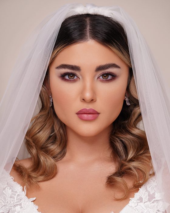 Kühle Pflaumen- und Mauve-Nuancen rahmen die Augen weich ein, während natürliche Nude-Lippen den Look klar, elegant und modern halten.