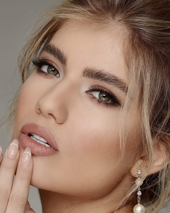 Moderner Nude-Bridal-Look mit weichen Brauntönen, gelifteter Augenform, dezenten Konturen und eleganten Perlenohrringen.