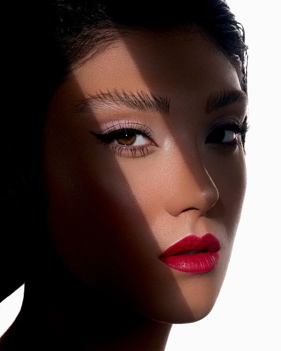 Editorial Beauty Look mit grafischer Lichtführung, präzisem Augen-Make-up und ausdrucksstarken roten Lippen.
