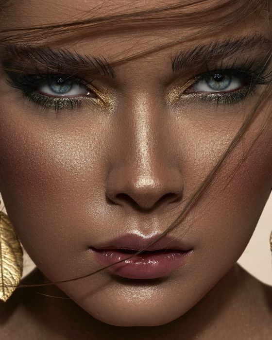 Editorial Make-up mit Smaragdgrün, Goldnuancen, strahlender Haut und glänzenden Nude-Lippen.