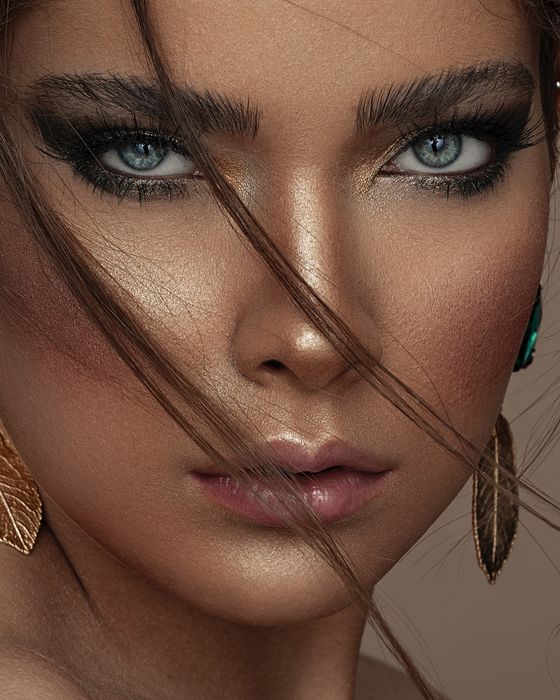 Editorial Make-up mit Smaragdgrün, Goldnuancen, strahlender Haut und glänzenden Nude-Lippen.