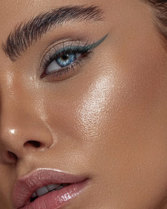 Futuristischer Editorial Look mit Aqua-Eyeliner, metallischen Reflexen, strahlender Haut und glänzenden Nude-Lippen.