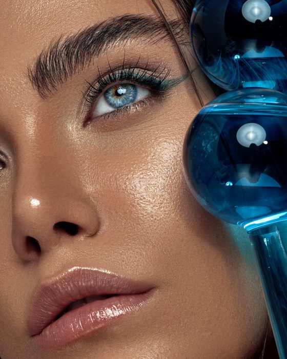 Futuristischer Editorial Look mit Aqua-Eyeliner, metallischen Reflexen, strahlender Haut und glänzenden Nude-Lippen.