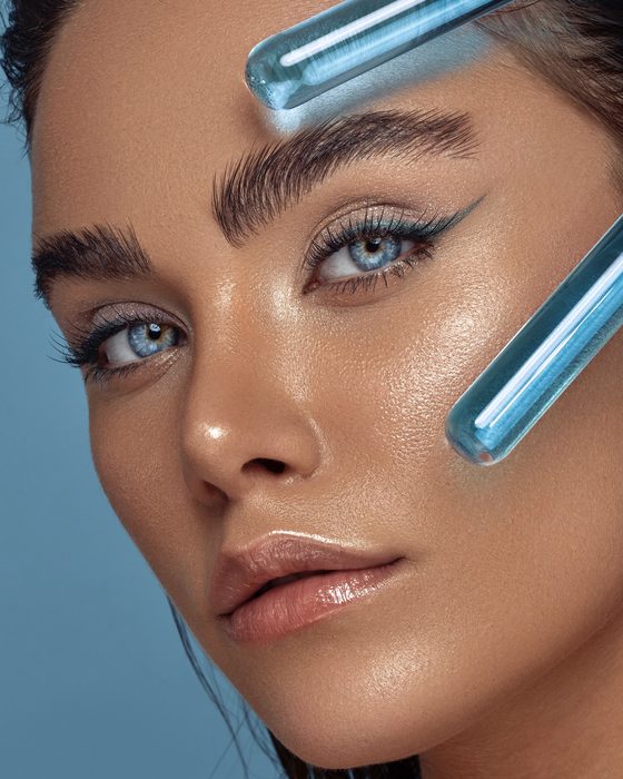 Futuristischer Editorial Look mit Aqua-Eyeliner, metallischen Reflexen, strahlender Haut und glänzenden Nude-Lippen.